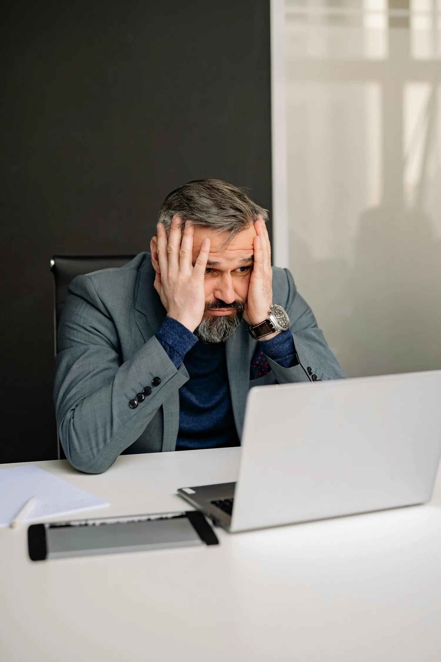 Empresário preocupado em frente ao notebook revisando números.